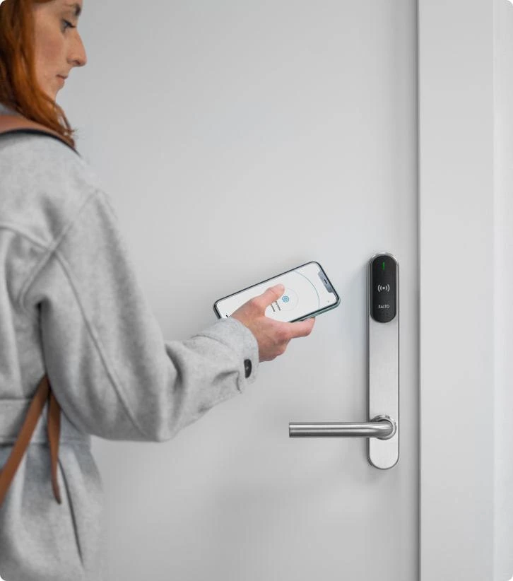 A person using a smartphone at a Salto electronic door lock.